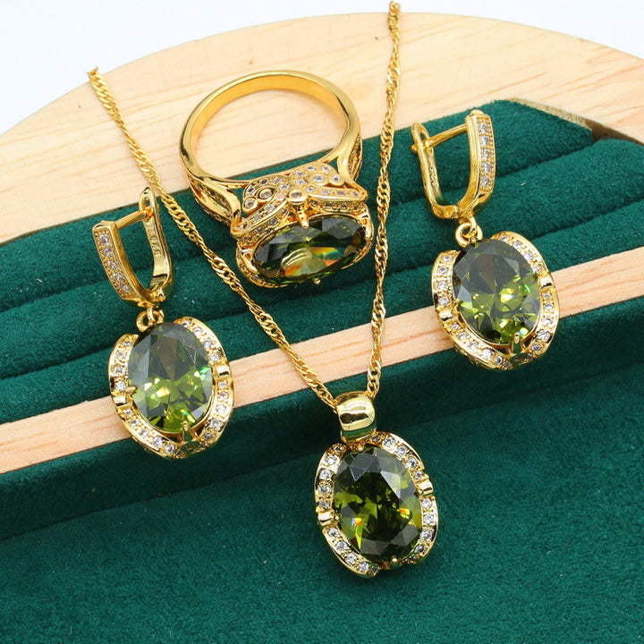 Gold-plated women’s jewelry set with oval green zirconia, including necklace, earrings, bracelet, and ring