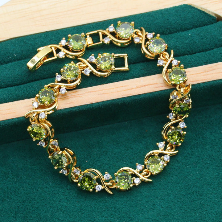 Gold-plated women’s jewelry set with oval green zirconia, including necklace, earrings, bracelet, and ring