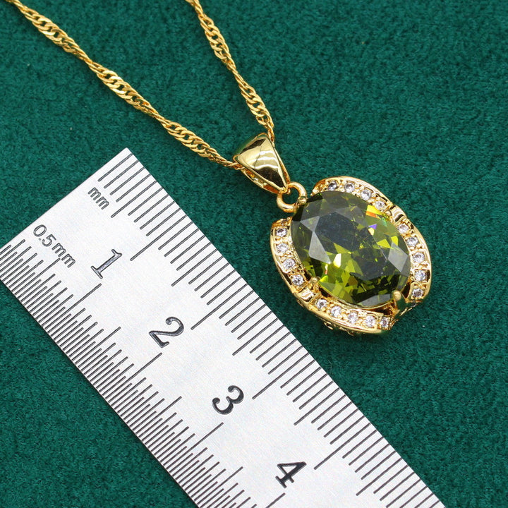Gold-plated women’s jewelry set with oval green zirconia, including necklace, earrings, bracelet, and ring
