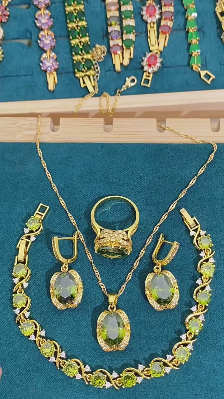 Gold-plated women’s jewelry set with oval green zirconia, including necklace, earrings, bracelet, and ring