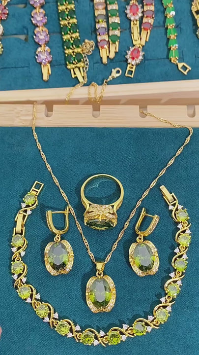 Gold-plated women’s jewelry set with oval green zirconia, including necklace, earrings, bracelet, and ring